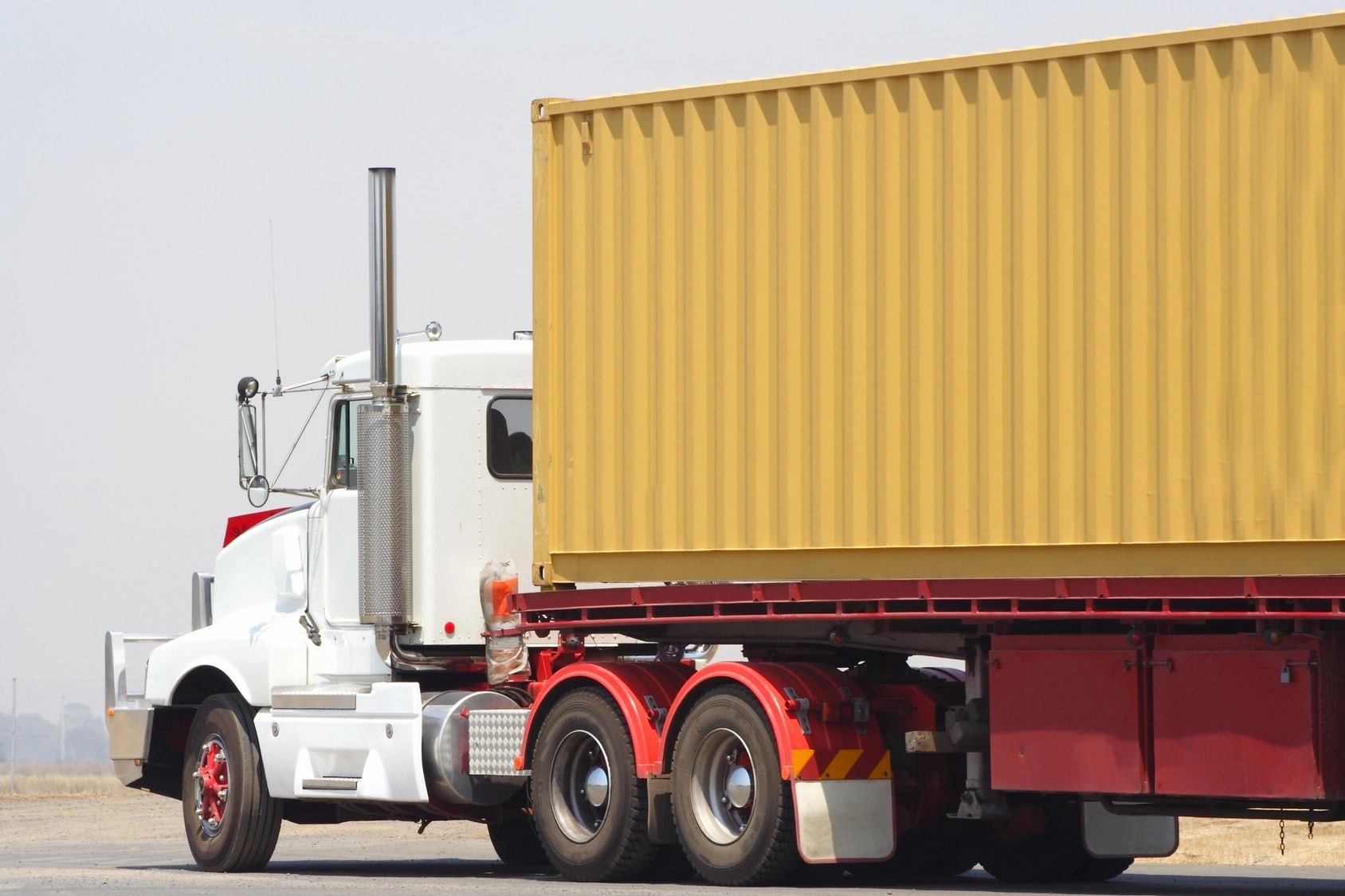 White semi-truck with yellow shipping container